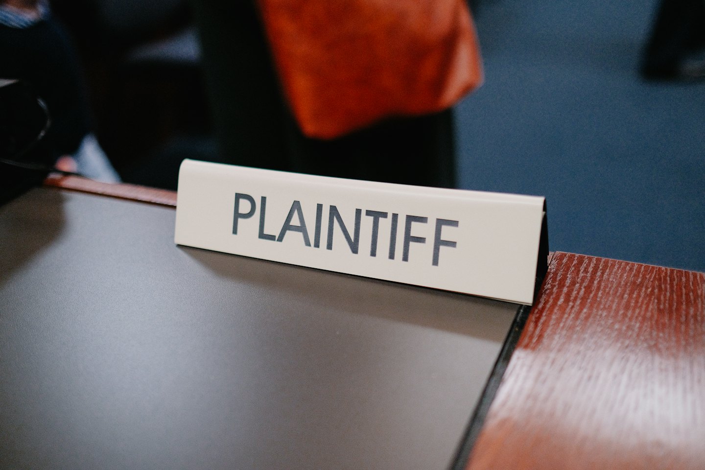 Beige nameplate with 'PLAINTIFF' on a dark gray desk.